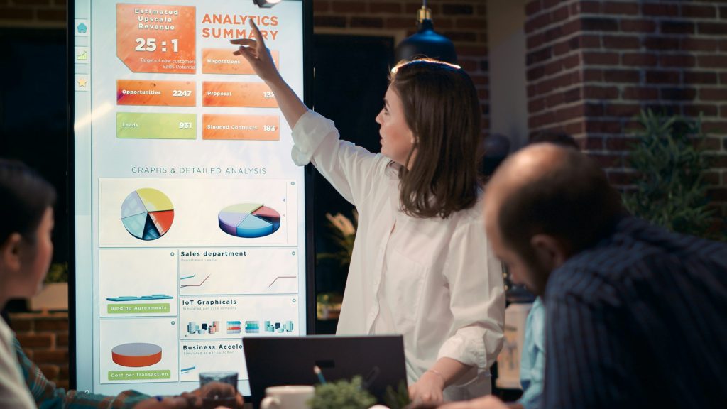 Businesswoman speaking in business meeting, holding laptop