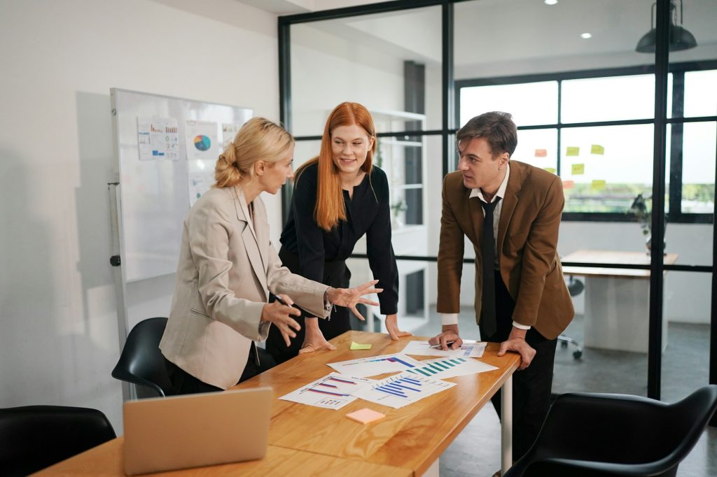 Three young business professionals standing together and discussing over business report